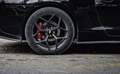 Close-up of a sleek black alloy wheel with subtle red accents on a sports car.