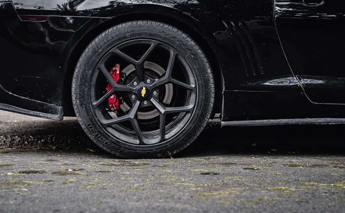 Close-up of a sleek car wheel with aggressive stance and custom brake calipers.