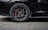 A close-up view of a sleek black car's wheel, featuring a detailed alloy wheel design and red brake calipers.