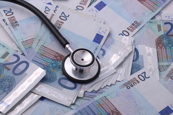 Stéthoscope posé sur une liasse de billets de vingt euros éparpillés