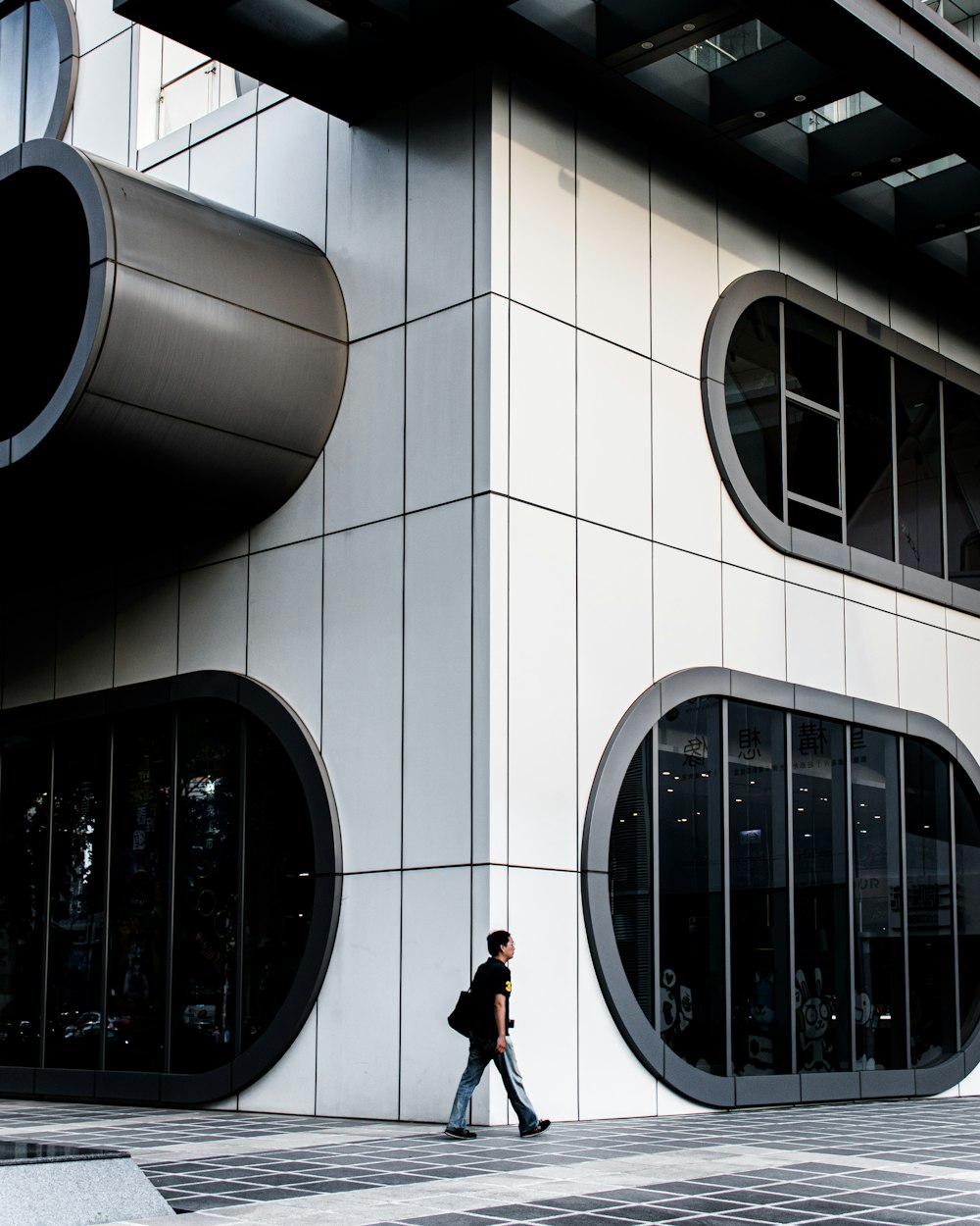 man in black jacket and black pants standing in front of white concrete building during daytime