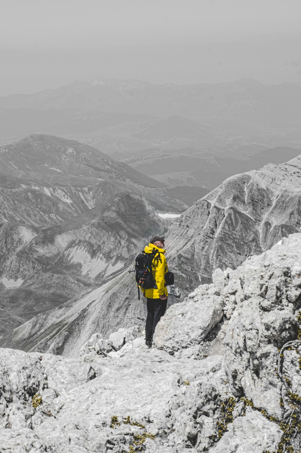 昼間、雪に覆われた山に立つ黄色いジャケットと黒いズボンを着た人