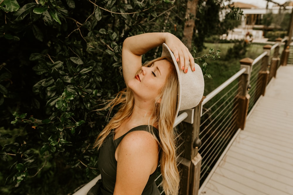 Femme en débardeur noir portant un chapeau fedora marron