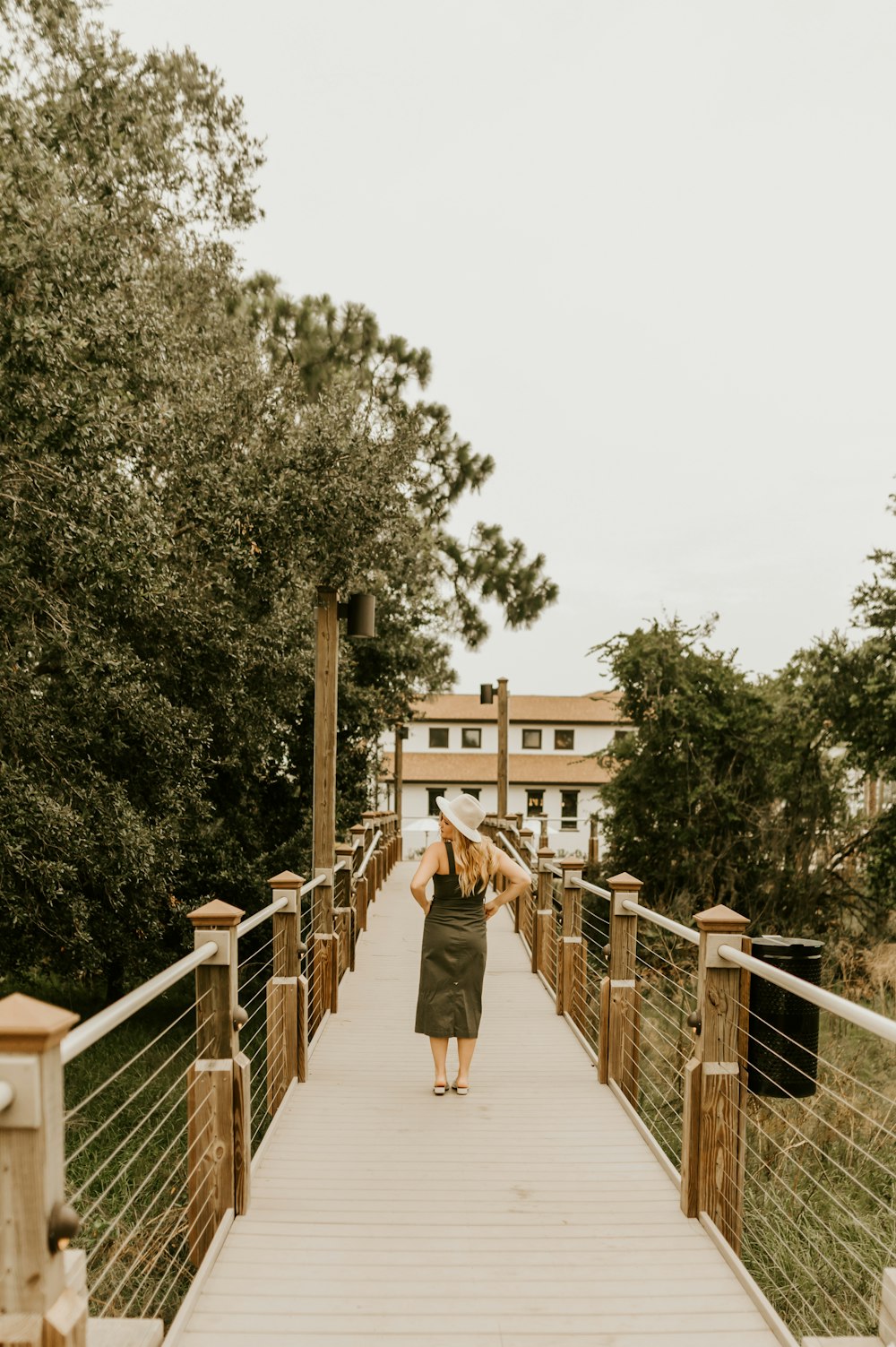 woman in brown coat walking on bridge during daytime