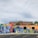 A vibrant mural on a building wall features various figures and signs with messages advocating for social justice. The artwork prominently includes phrases like 'Black Lives Matter,' and other calls for societal change. The imagery uses a mix of colors and geometric patterns as a backdrop, with figures wearing masks, highlighting themes of activism and awareness.