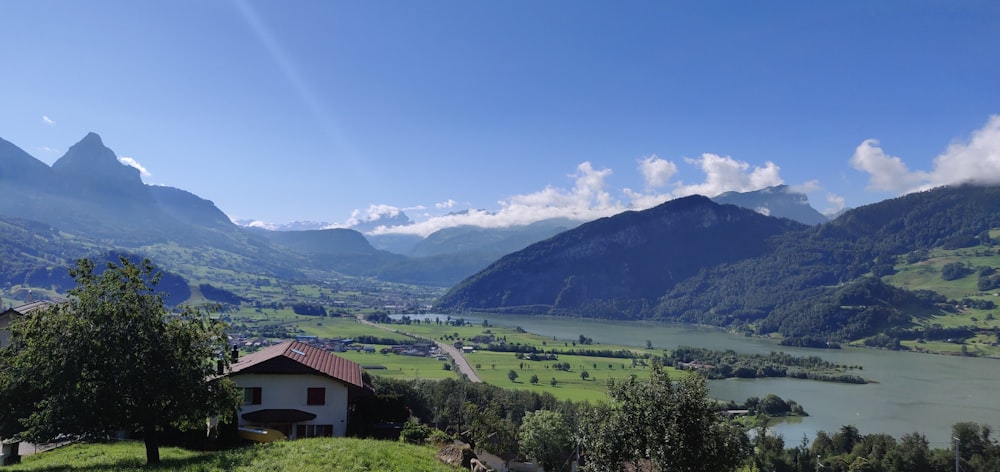 white and brown house near green mountains under blue sky during daytime