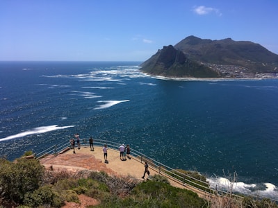people walking on brown dirt road near body of water during daytime