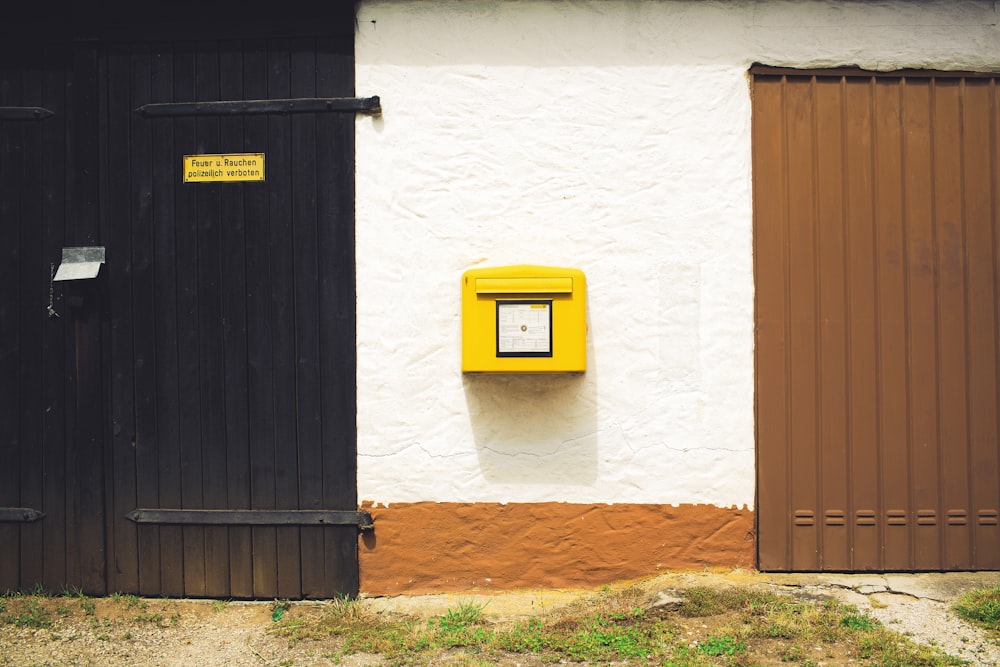 blue and yellow trash bin beside white wall