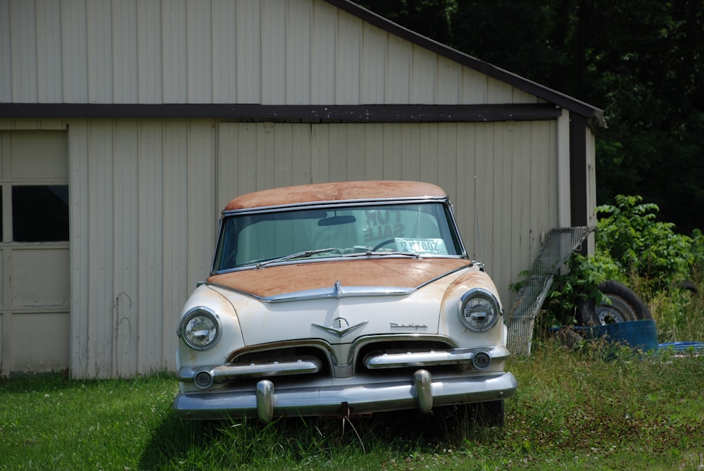 auto d'epoca marrone e bianca parcheggiata accanto alla casa di legno marrone