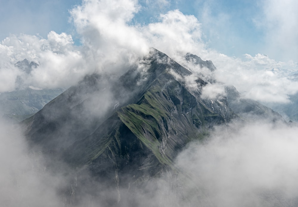 montaña verde bajo nubes blancas durante el día