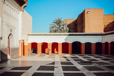 brown and white concrete building near palm tree under blue sky during daytime