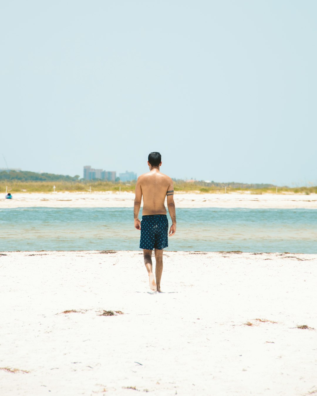 man in blue shorts walking on beach during daytime