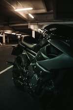 A sleek motorcycle parked inside a modern garage, bathed in moody lighting highlighting its chrome details.