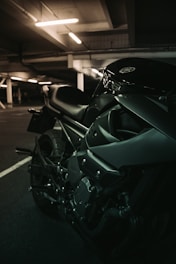 A sleek black motorcycle parked in a minimalist urban garage with warm lighting.