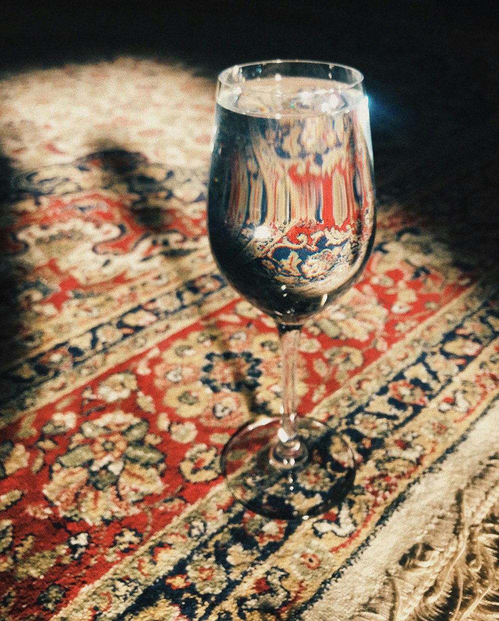 clear wine glass on red and brown floral textile