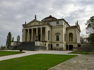 Grand entrance of a stately home with tall pillars and manicured lawn.