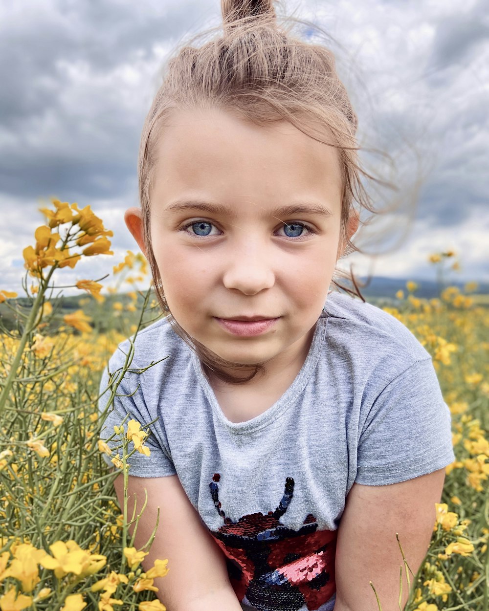a little girl sitting in a field of yellow flowers