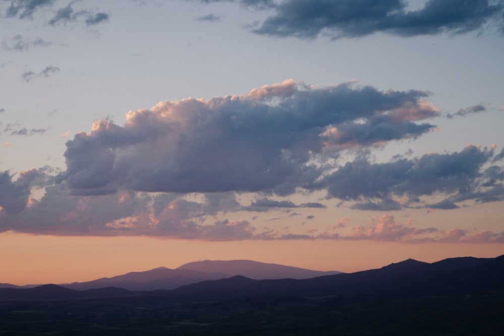 silhouette of mountains under cloudy sky during sunset