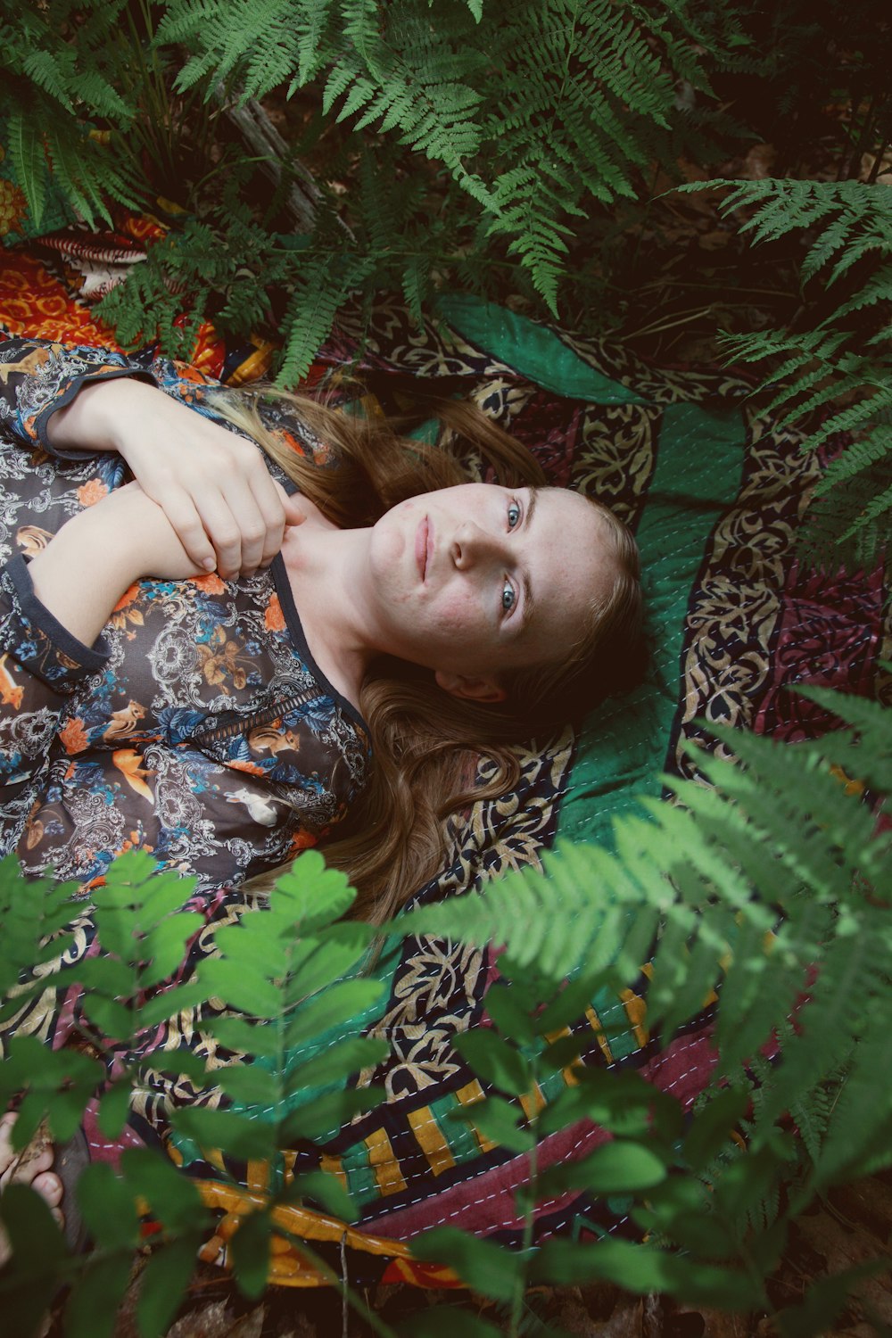 woman in blue and white floral dress lying on green leaves