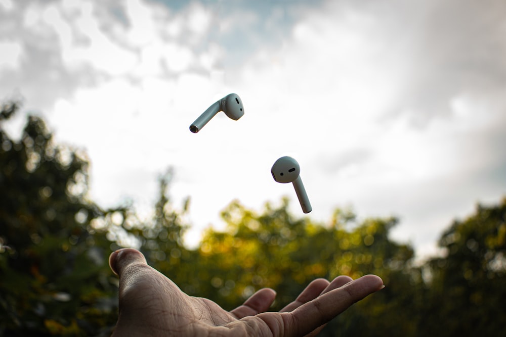 person holding apple earpods during daytime