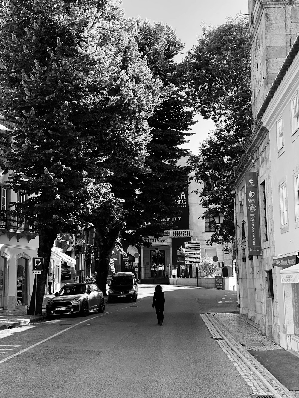 grayscale photo of man walking on sidewalk