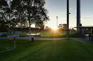 Wide view of a sports field with an irrigation system in operation during sunset.