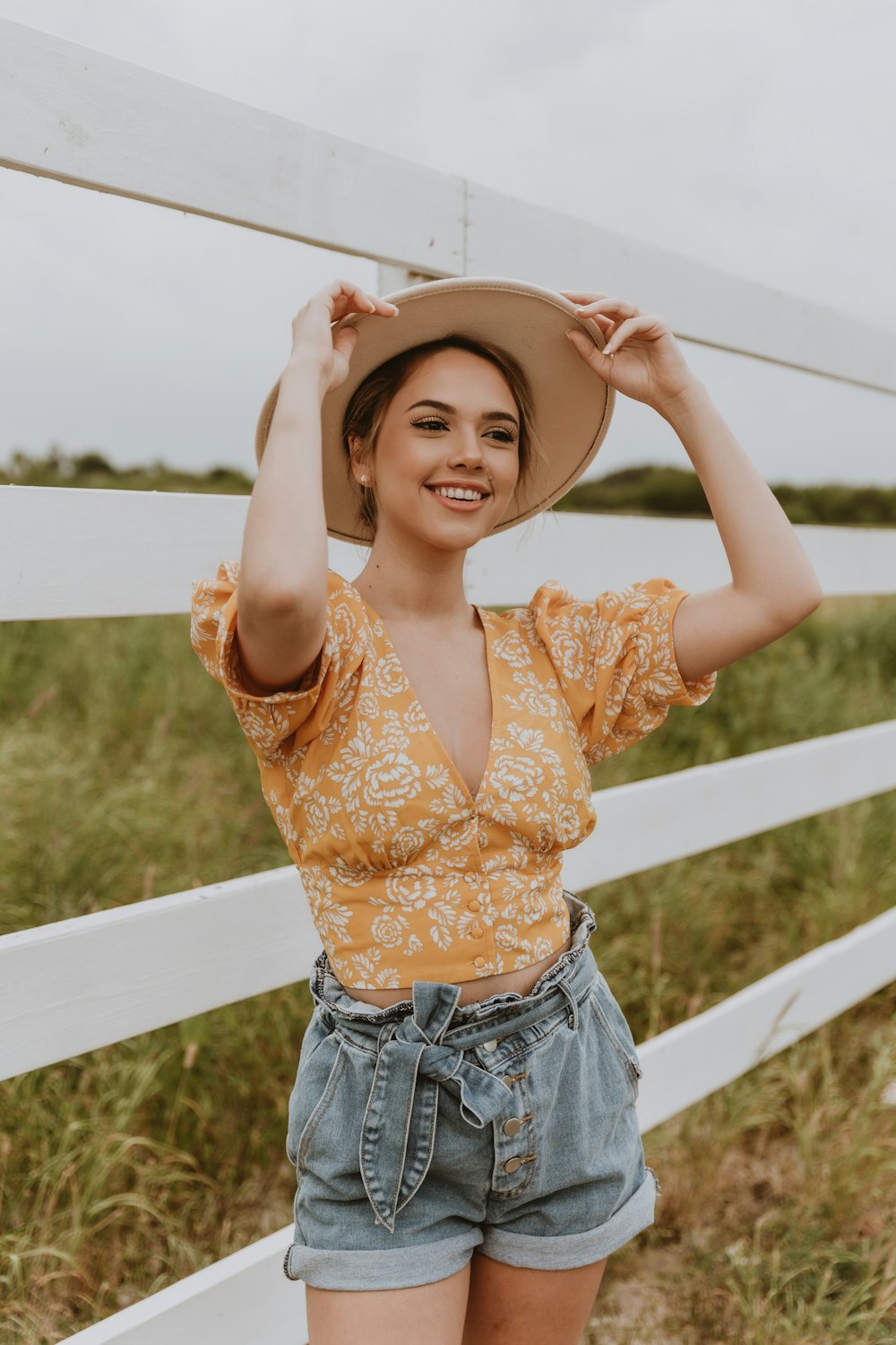 mulher no top floral marrom da colheita e shorts jeans azuis vestindo chapéu marrom