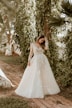 woman in white wedding dress standing near green trees during daytime