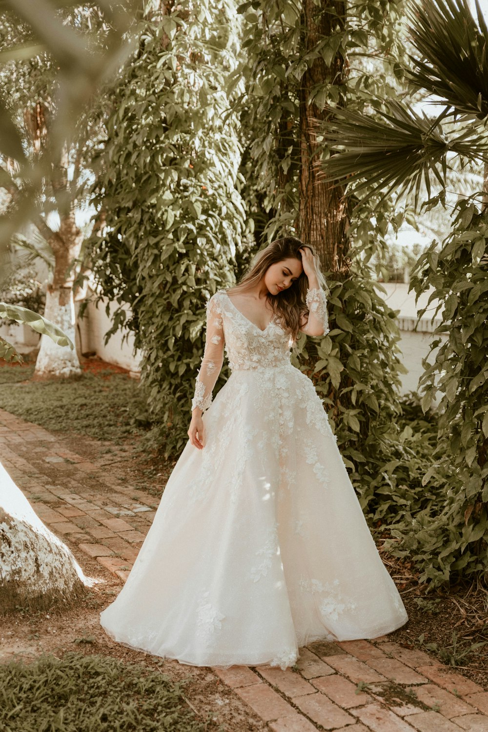 woman in white wedding dress standing near green trees during daytime