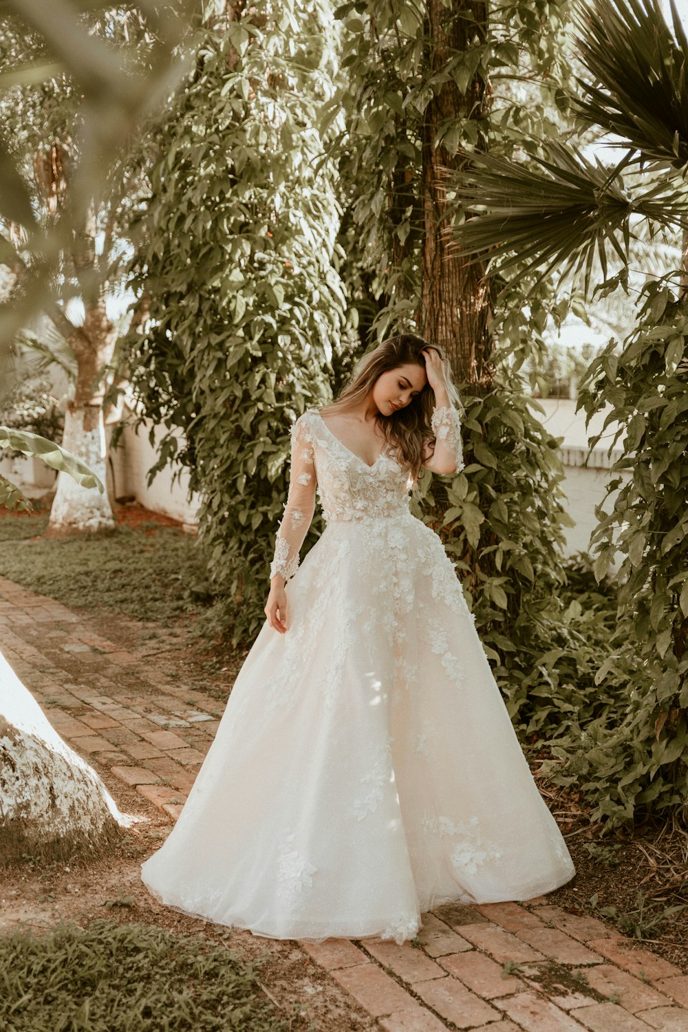 donna in abito da sposa bianco in piedi vicino agli alberi verdi durante il giorno