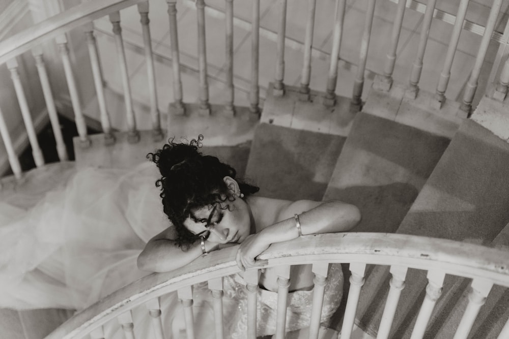grayscale photo of woman lying on staircase