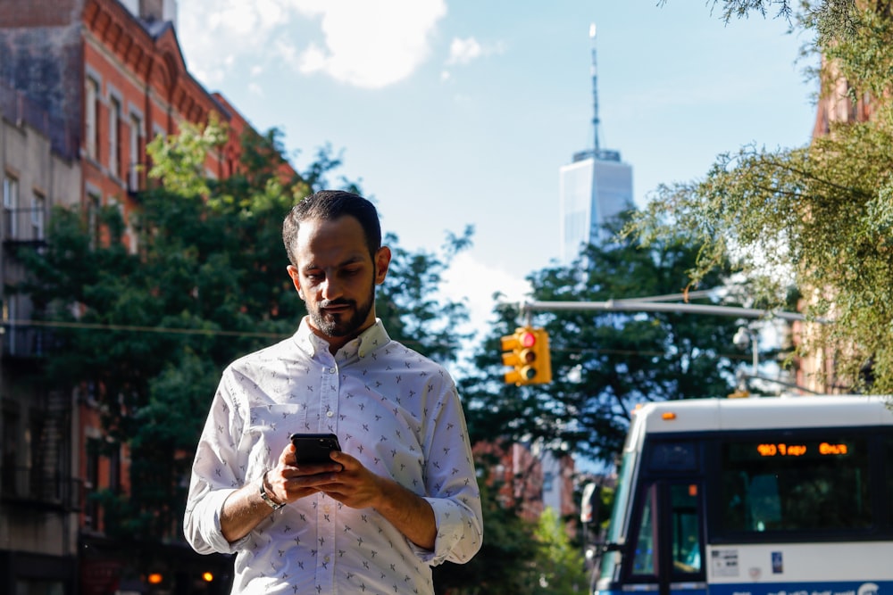 man in white button up shirt holding black smartphone