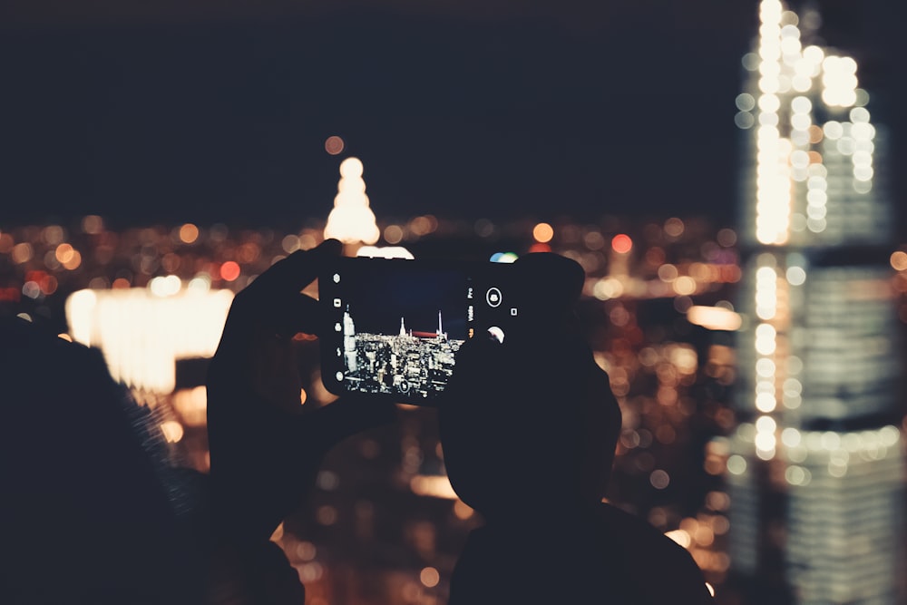 a person taking a picture of a city at night