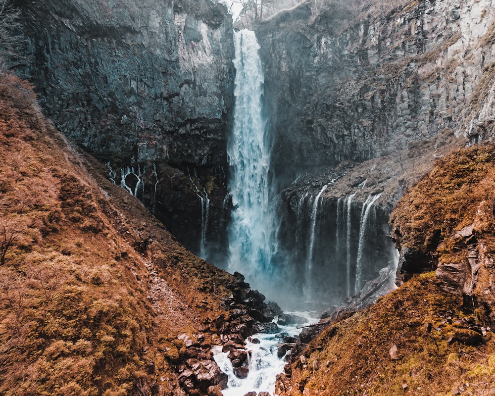 waterfalls in brown rocky mountain during daytime