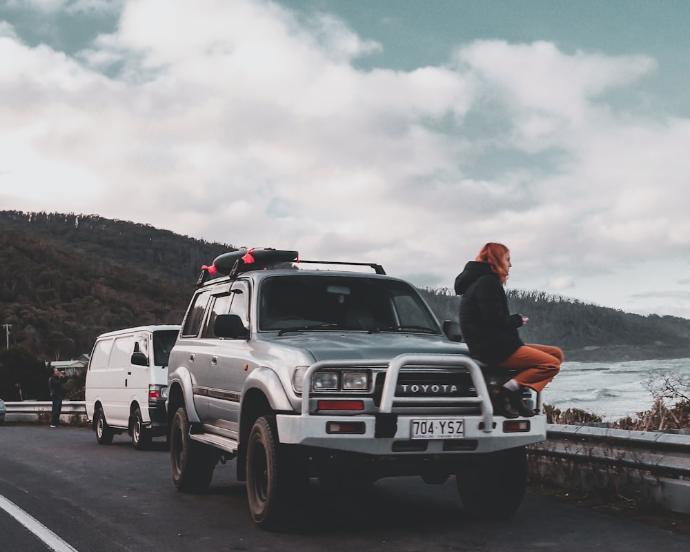 man in red jacket sitting on white suv