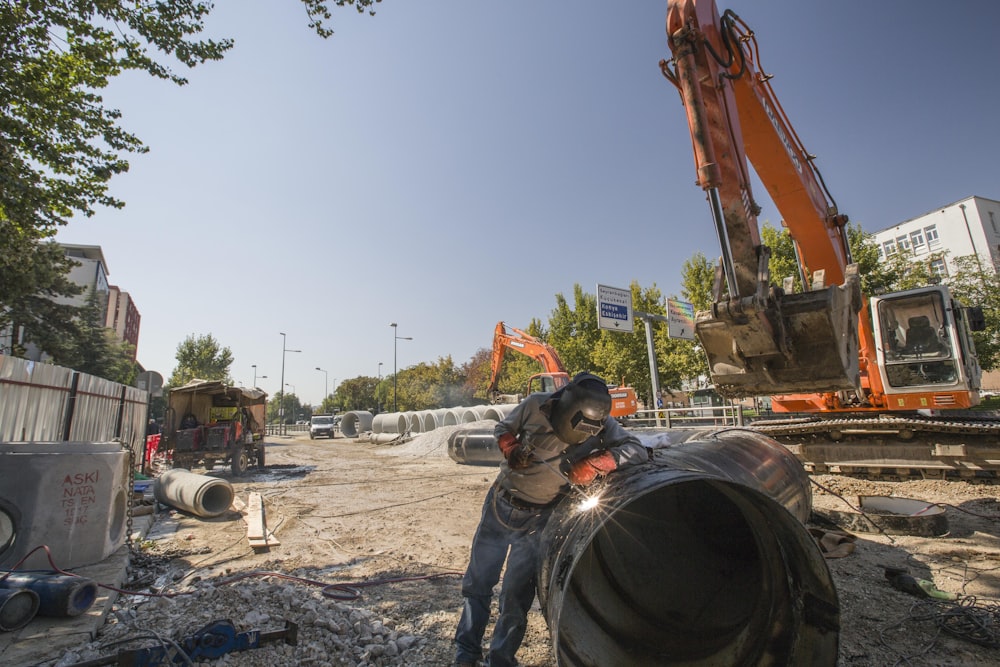 man in black jacket and black helmet holding orange and black heavy equipment