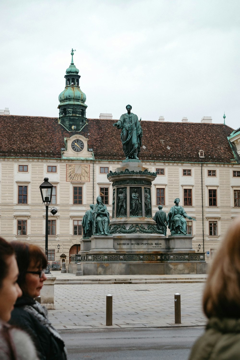 man in black jacket standing near statue during daytime