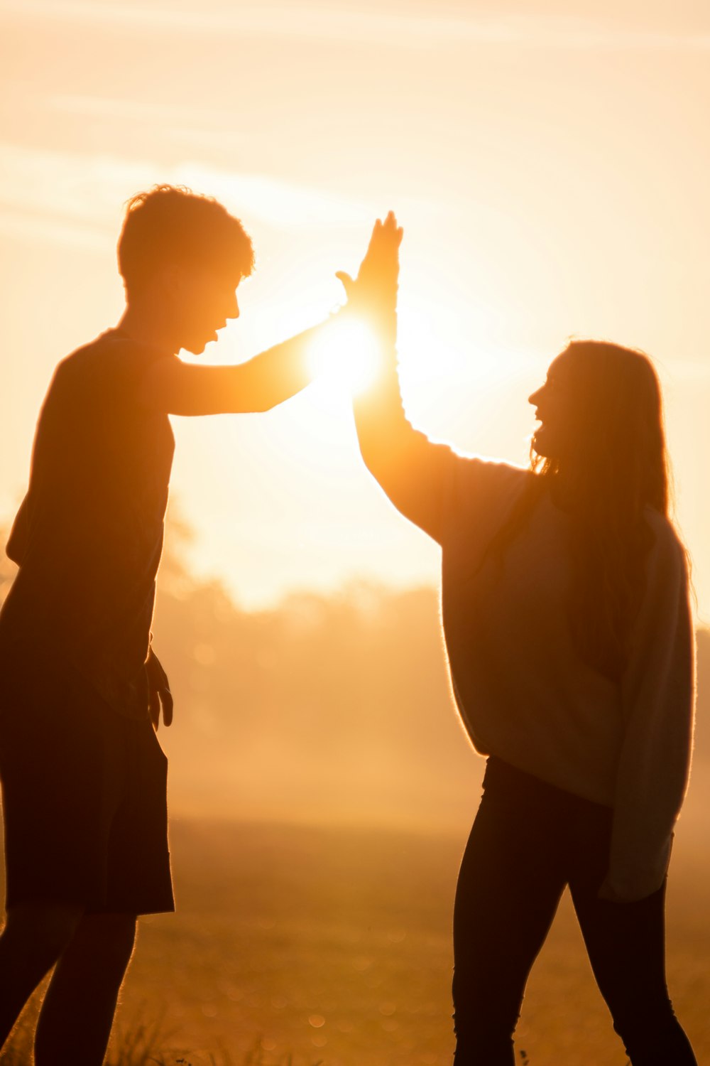 Silhouette von Mann und Frau, die sich während des Sonnenuntergangs an den Händen halten