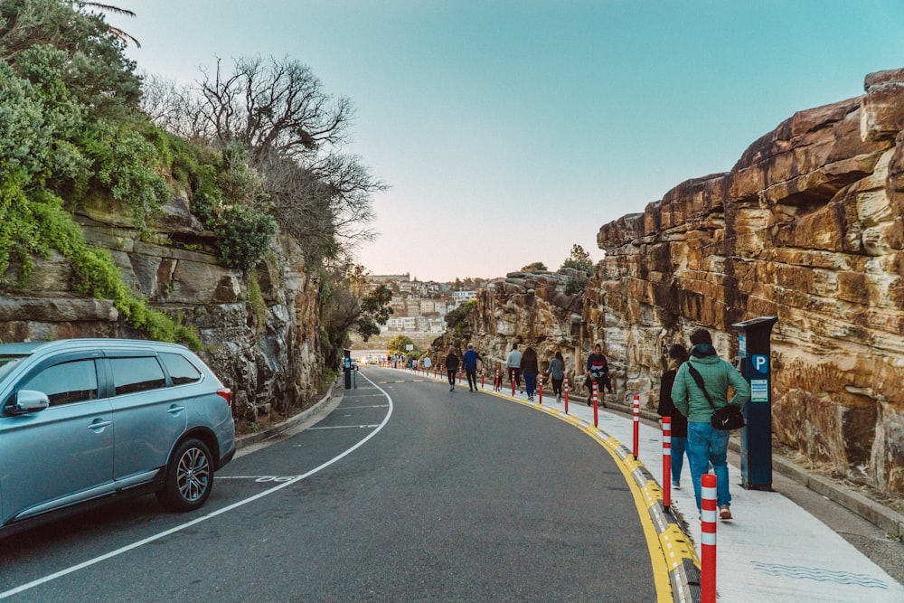 people walking on road near brown rock formation during daytime