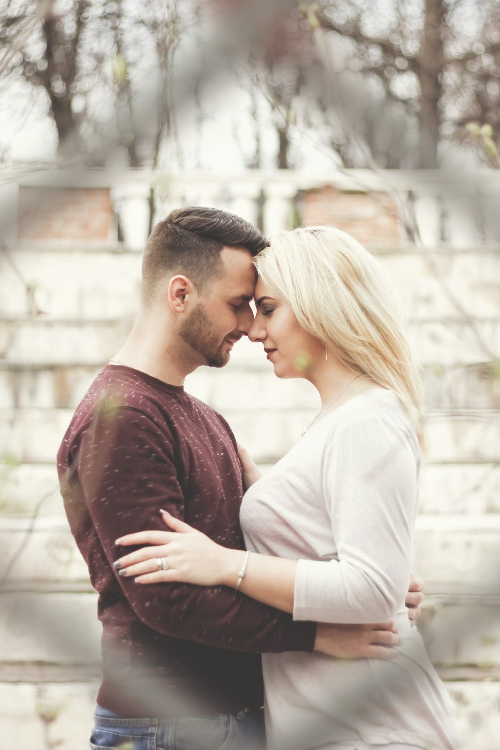 man in maroon crew neck shirt kissing woman in white long sleeve shirt