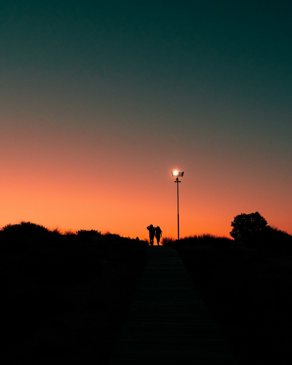 silhouette of people walking on pathway during sunset