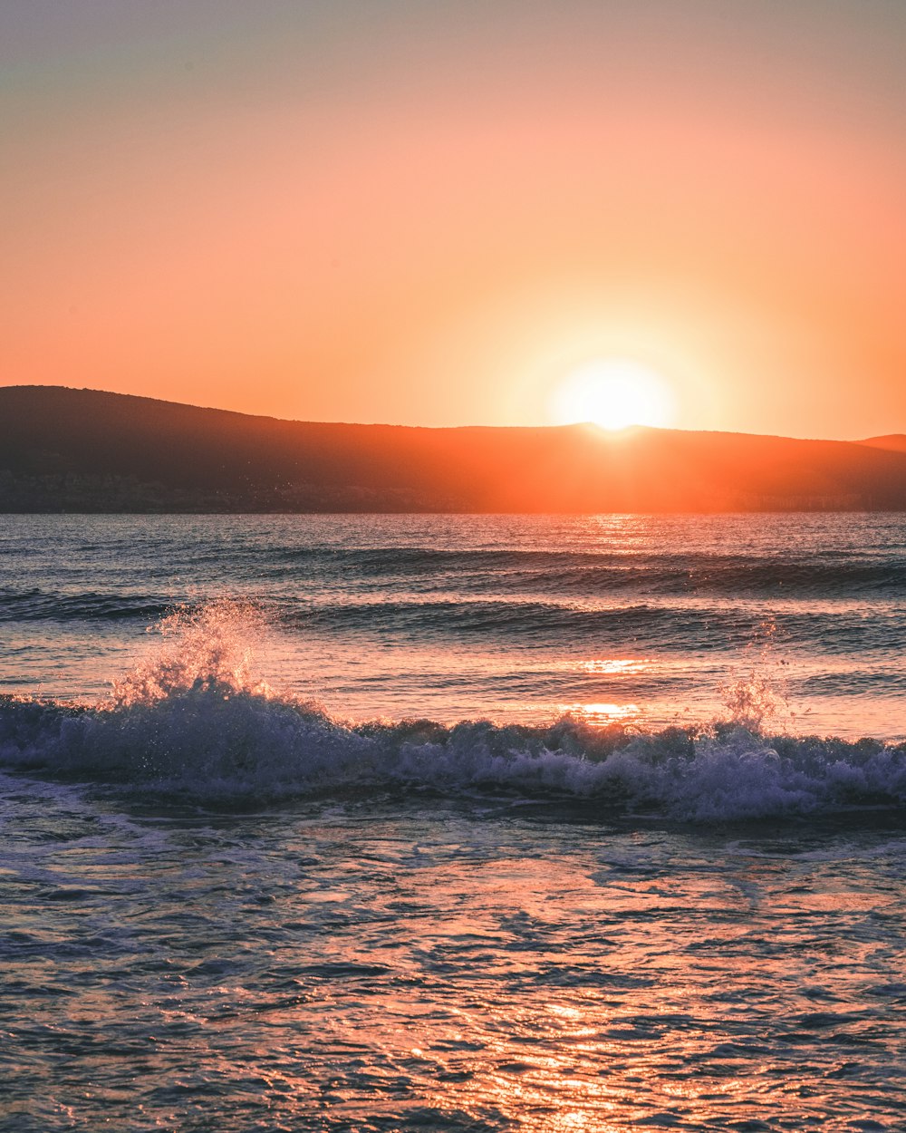 ocean waves crashing on shore during sunset