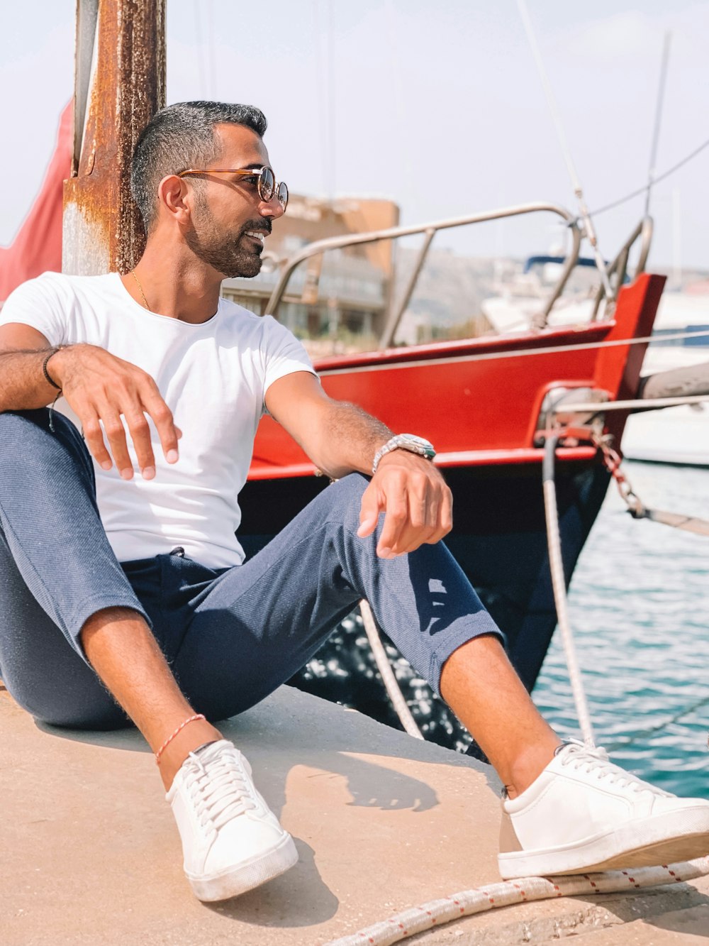 man in white crew neck t-shirt and blue denim jeans sitting on boat during daytime