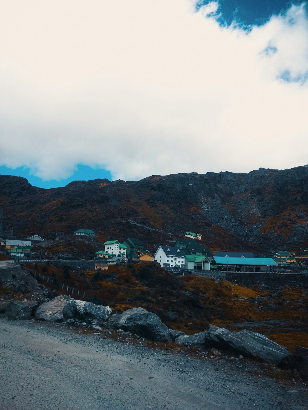 white and green house near brown mountain under white clouds during daytime