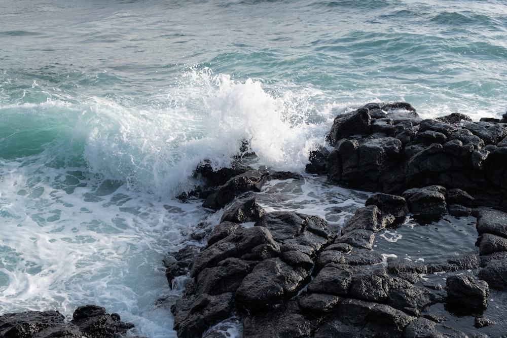 roches noires sur le bord de la mer pendant la journée