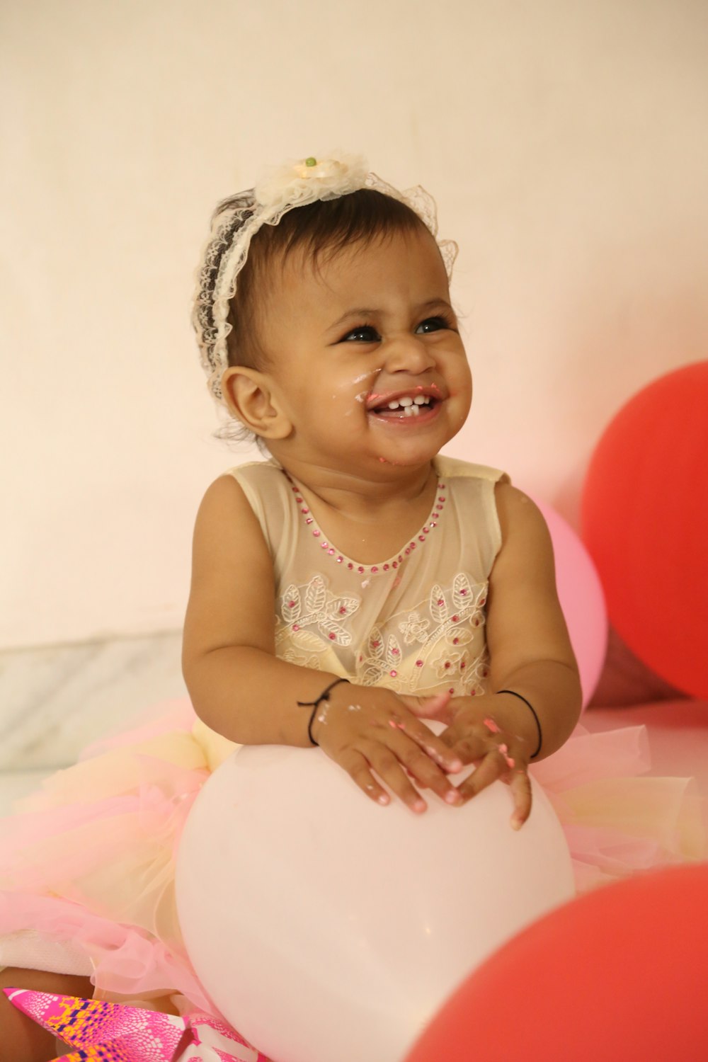 girl in white sleeveless dress sitting on pink bed