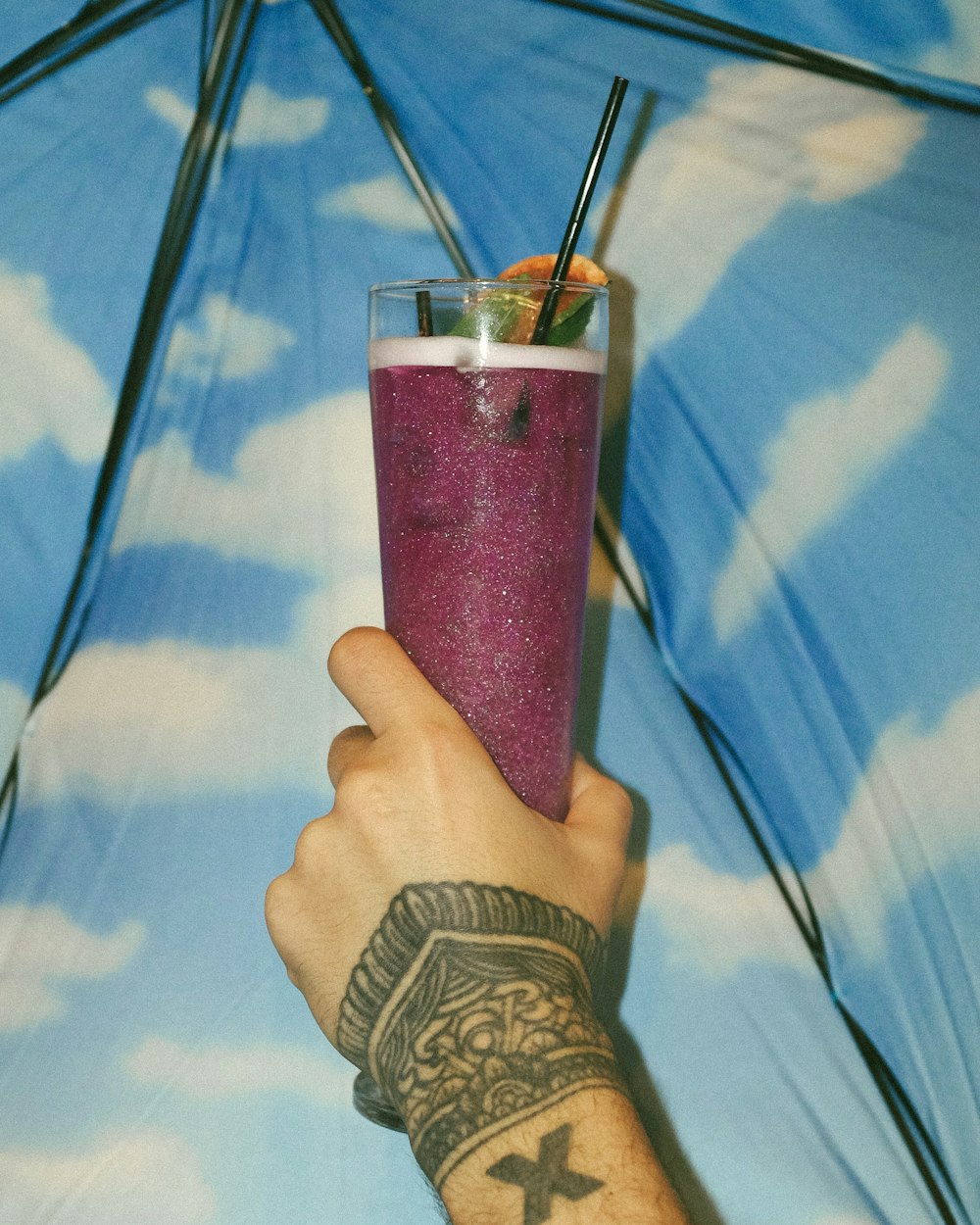 person holding clear drinking glass with pink liquid