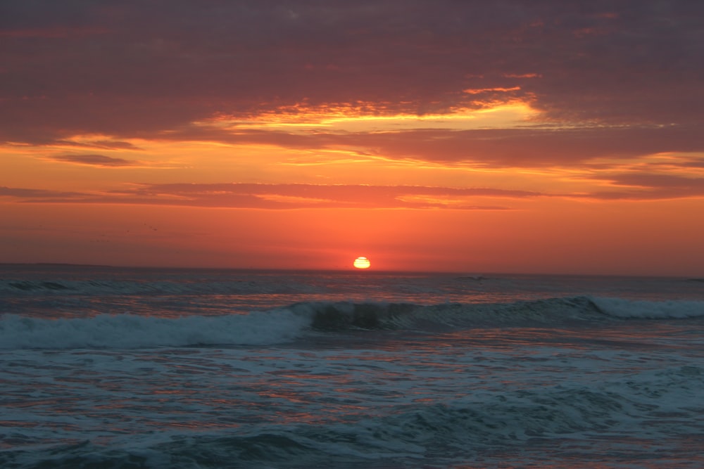 ocean waves crashing on shore during sunset