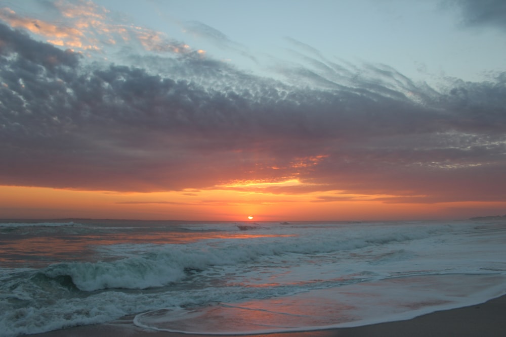 Olas del océano rompiendo en la costa durante la puesta de sol