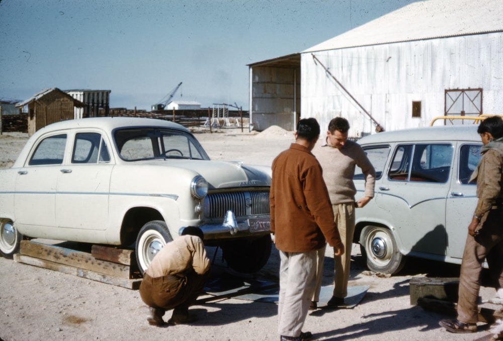 man in brown button up shirt standing beside white car during daytime